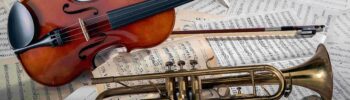foto di un violino e una tromba disposti sopra a degli spartiti